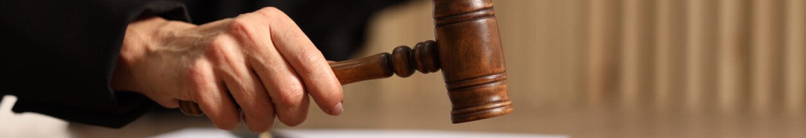 Judge striking mallet at wooden table indoors, closeup. Space for text